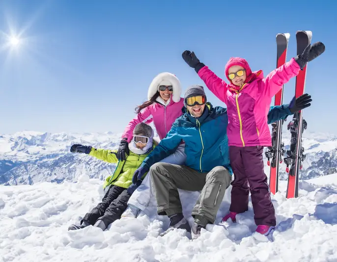 Laughing family in winter vacation with ski sport on snowy mountains. Happy man and woman with sons having fun and looking at camera. Family with two children enjoying winter holiday at ski resort.
