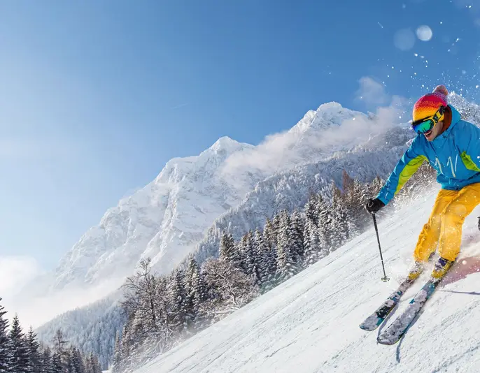 Skier skiing downhill during sunny day in high mountains